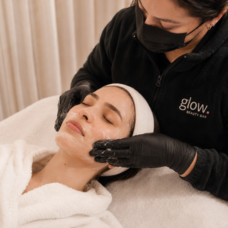Profesional de Glow Beauty Bar realizando una limpieza facial manual a una clienta.