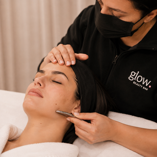 Profesional de Glow Beauty Bar realizando un tratamiento facial con herramienta estética en el rostro de una clienta.